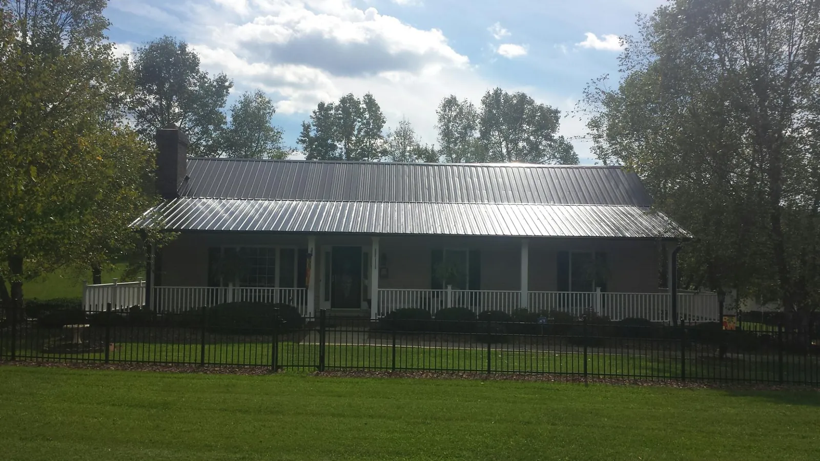 Gray metal roof on a brick ranch with a full width front porch — Gutter Guard Installation work by our crew in Garwood