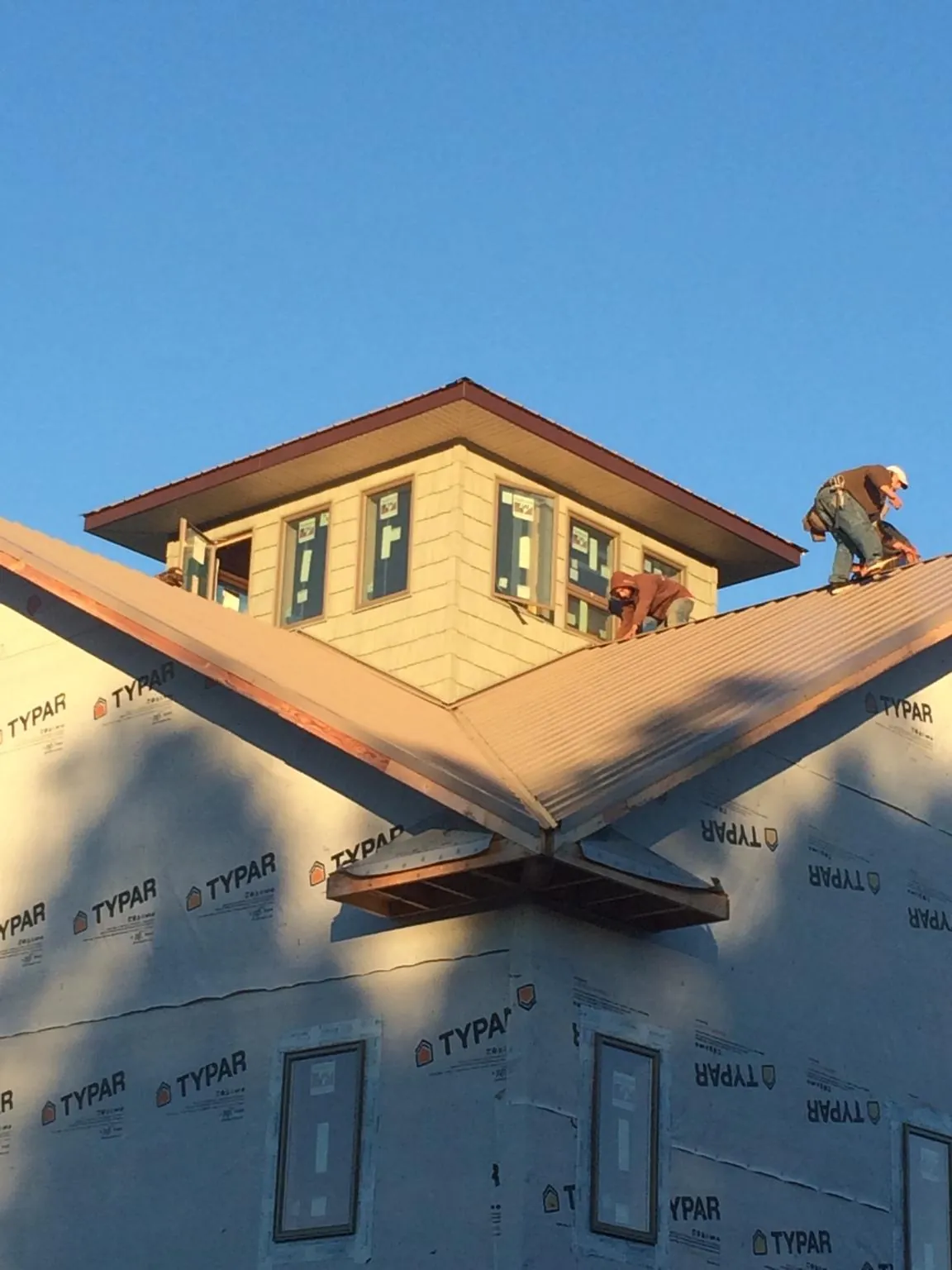 Roofers working around a rooftop cupola on a new metal roof at sunset — Roof Waterproofing in Garwood by Roofing Brothers